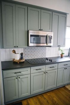 a kitchen with gray cabinets and black counter tops