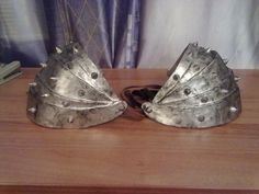 two metal crowns sitting on top of a wooden table