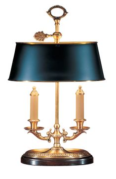 a table lamp with a black shade on top and two candles in the middle,