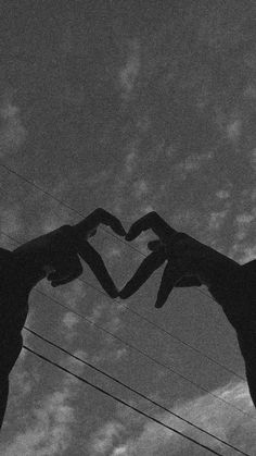 two giraffes making a heart shape with their hands in front of the sky