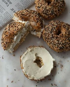 bagels with cream cheese and sesame seeds are on a paper towel next to an open book