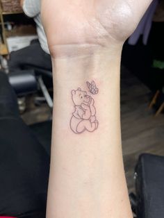 a small tattoo on the wrist of a woman with a bear and butterfly in it