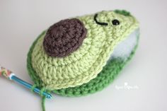 a green crocheted hat with a button on the side and a yarn ball in the middle