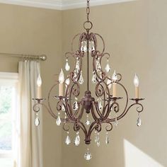 a chandelier hanging from the ceiling in a room with beige walls and curtains