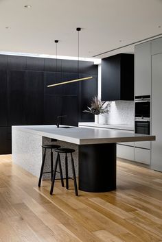 a modern kitchen with black cabinets and white countertops is pictured in this image, the island has two stools on it