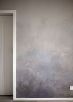 an empty room with a white door and gray wall