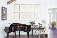 there is a grand piano in the living room with pictures on the wall behind it