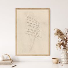 a white table with a vase and some flowers on it next to a framed art piece