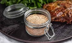 a plate topped with meat and vegetables next to a jar of seasoning on top of a table