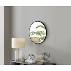 a round mirror on the wall above a table with a lamp and other items in front of it