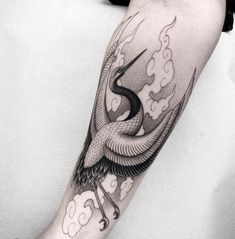 a man's arm with a bird and clouds tattoo on it