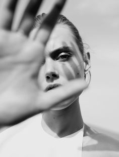 a black and white photo of a woman's face with her hands in the air