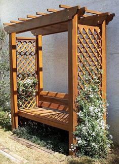 a wooden gazebo sitting next to a wall with flowers growing on the top and bottom