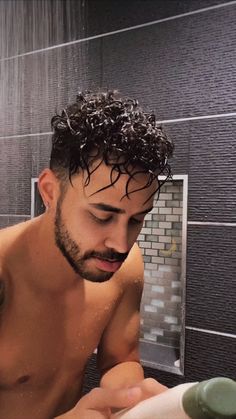 a shirtless man in the shower brushing his teeth