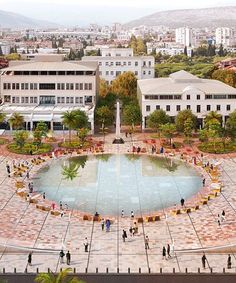 an aerial view of people walking around a fountain in the middle of a city square