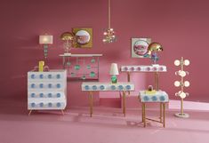 a room with pink walls and furniture in the center, including two tables that have blue polka dots on them