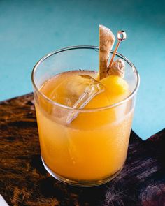 an orange drink in a glass with a garnish on the top and a toothpick sticking out of it