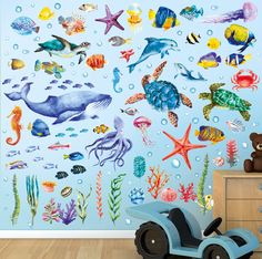 a child's room with an ocean theme wall decal and toy car in the foreground