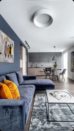 a living room filled with furniture and a painting on the wall next to a coffee table