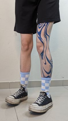 the legs and ankles of a man with tattoos on them, both wearing black shorts