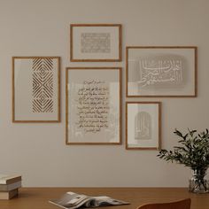 a wooden table topped with a book and vase filled with flowers next to pictures on the wall