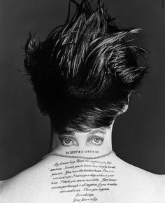 the back of a woman's head with feathers on her neck and words written in cursive writing