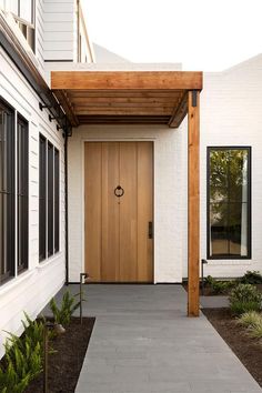 a white house with a wooden front door and walkway leading up to the entryway