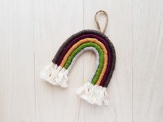 a rainbow ornament hanging on a white wooden wall with a string attached to it