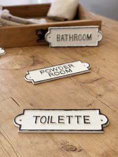 three bathroom signs sitting on top of a wooden table