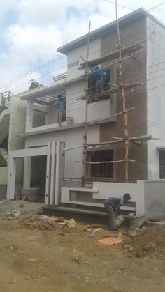 two men are working on the side of a building that is being built with scaffolding