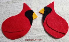 two red birds with yellow beaks sitting on top of a white sheet and one is facing each other