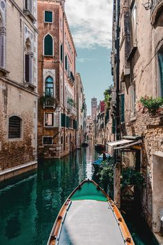 a boat traveling down a canal next to tall buildings and greenery on both sides