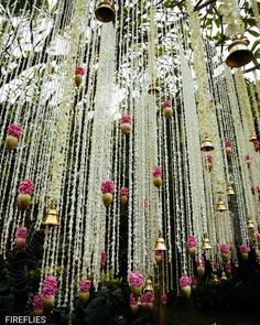 a bunch of flowers hanging from the ceiling in front of a tree with lots of lights on it