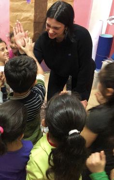 a woman standing in front of a group of children