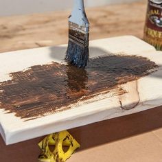 a paintbrush is sitting on top of a piece of wood that has been stained brown