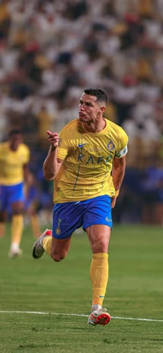 a soccer player in yellow and blue runs with the ball while other players look on