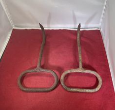 an old pair of scissors sitting on top of a red cloth next to each other