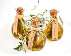 three small bottles filled with olive oil on top of a white plate and tied with twine