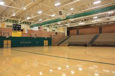 an empty basketball court with green and yellow banners on the sidelines in a gym