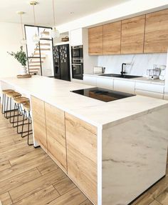 a modern kitchen with an island countertop and stools in front of the sink