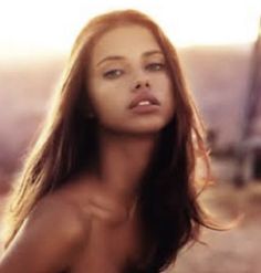 a woman with very long hair posing for a photo in front of the sun light