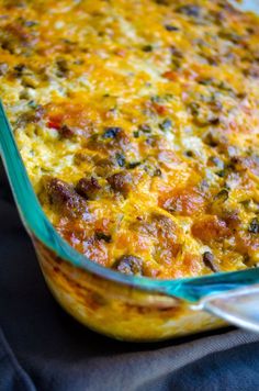 a casserole dish with meat and vegetables in it on a blue cloth next to a fork