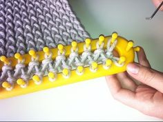 a person is holding a yellow knitting needle