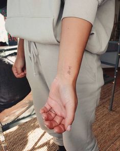 a woman holding her hand with a small cross tattoo on it's left wrist