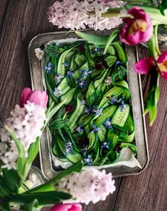 fresh cut flowers in a metal tray on a wooden table with purple and pink tulips