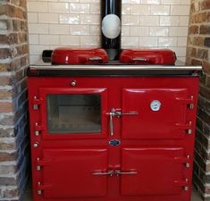 an old fashioned red stove in a brick wall