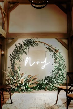 the wedding sign is lit up in front of an archway with greenery and flowers