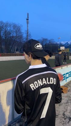 a man standing on top of a baseball field next to a wall with the number 7 on it