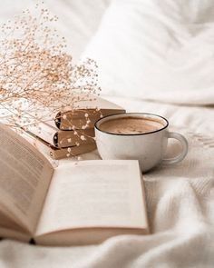 a cup of coffee and an open book on a bed