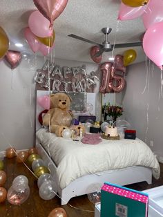 a teddy bear sitting on top of a bed in a room filled with balloons and confetti